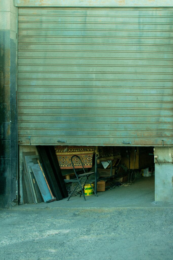 Partial view of a garage entrance with various items stored inside, exuding an urban industrial vibe.